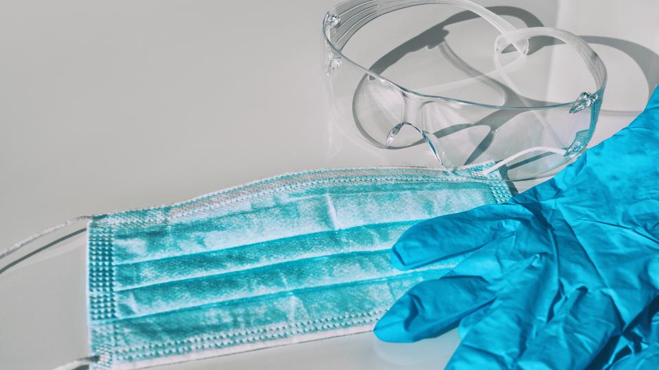 ppe on a table including gloves a mask and safety goggles
