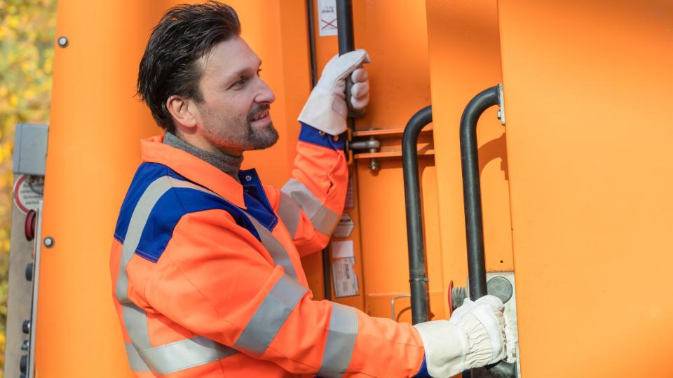 happy waste collector smiling at bin lorry