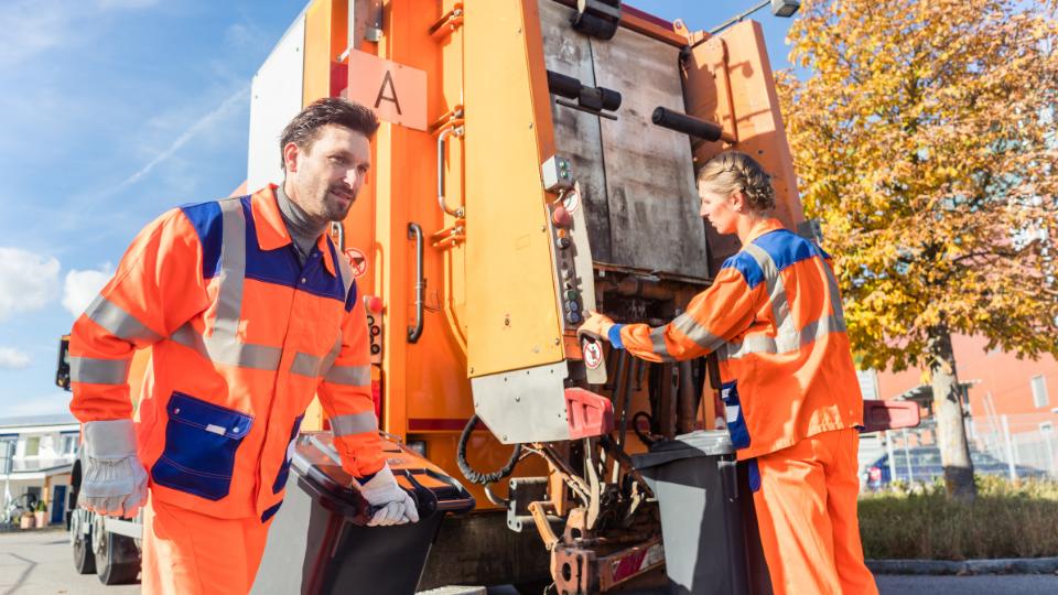 two waste collectors putting commercial waste in a waste lorry