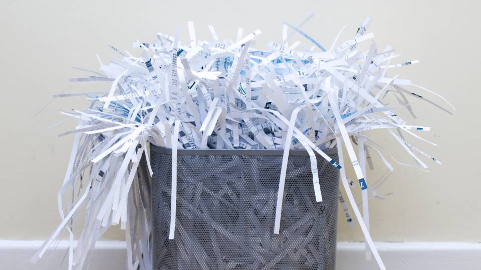 office paper bin overflowing with shredded paper