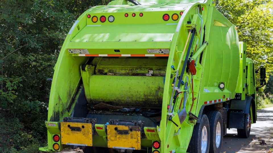 A photograph of a green bin lorry collecting commecial waste
