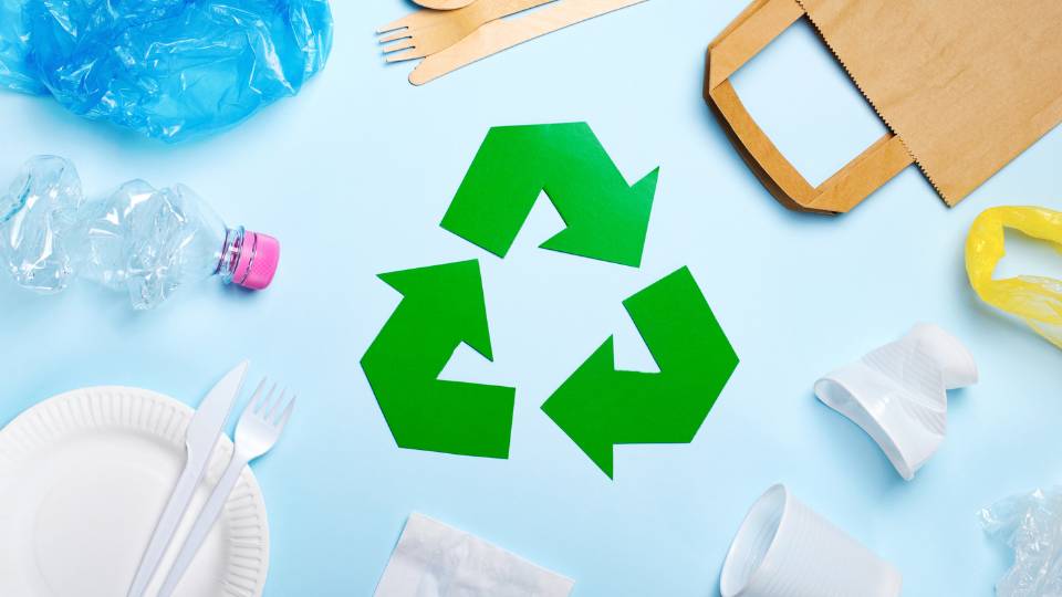 Green recycling symbol non a table with recycling material around it