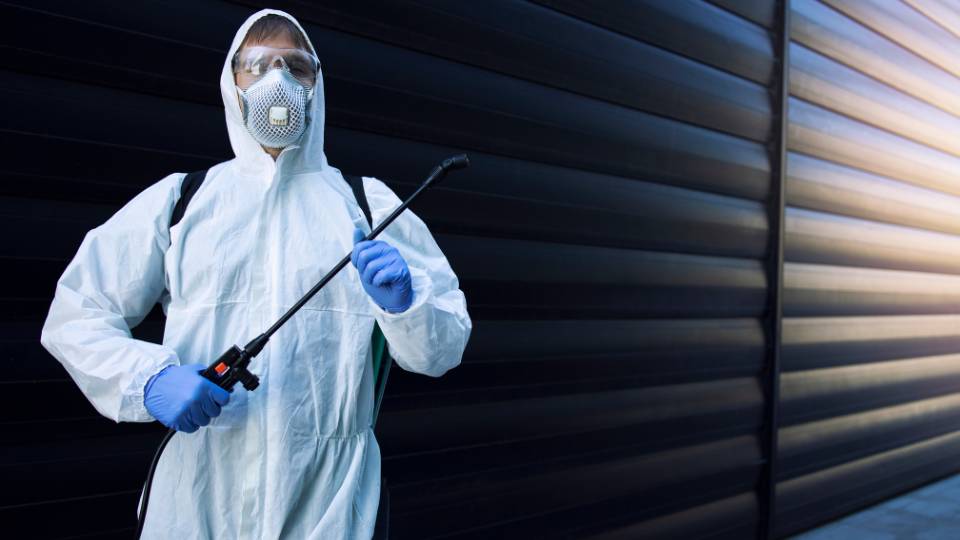 pest control worker with protective gear on and sprayer