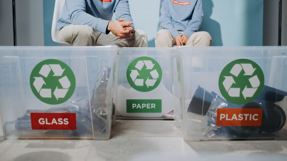 A photograph of someone sorting dry mixed recycling into recycling bins.