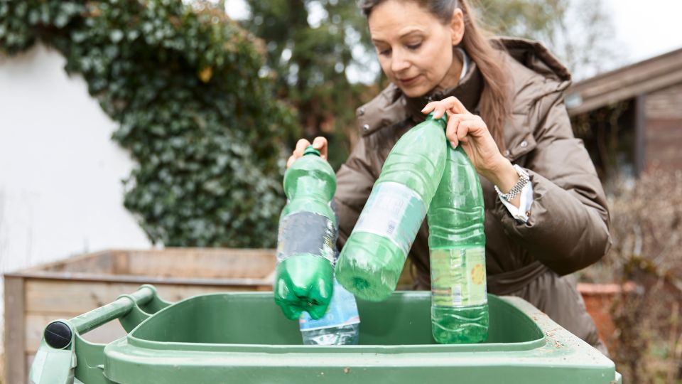 A photograph of a woman putting recycling in the bin