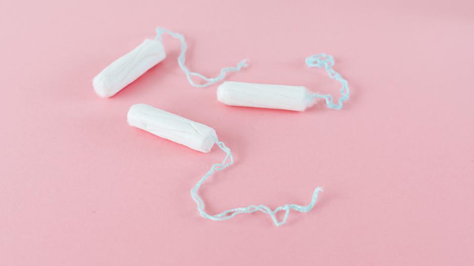 three individual tampons on a pink background