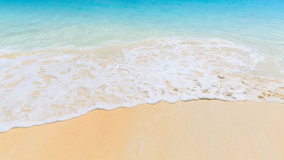 a beach with a wave coming in during the summer
