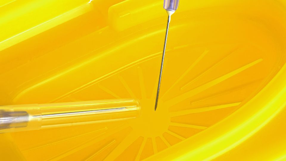 A photograph of a sharps waste bin being used for tattoo needle disposal
