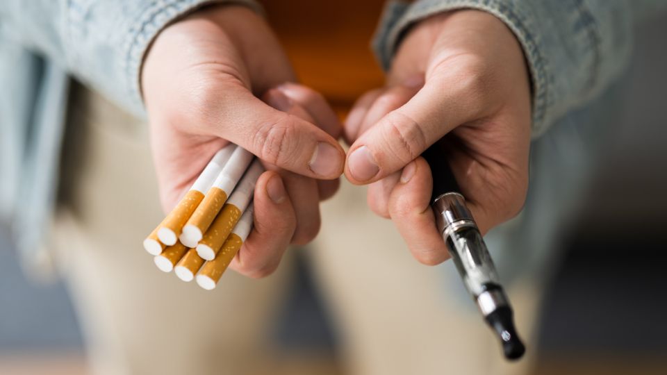 Cigarettes and e-cigarette being helf by a person.
