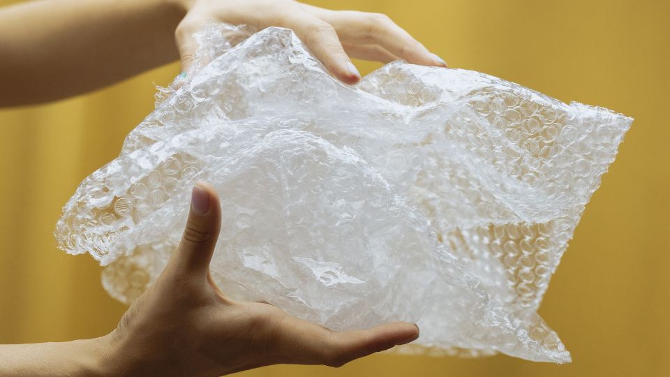 Crumpled bubble wrap waste in a persons hand.