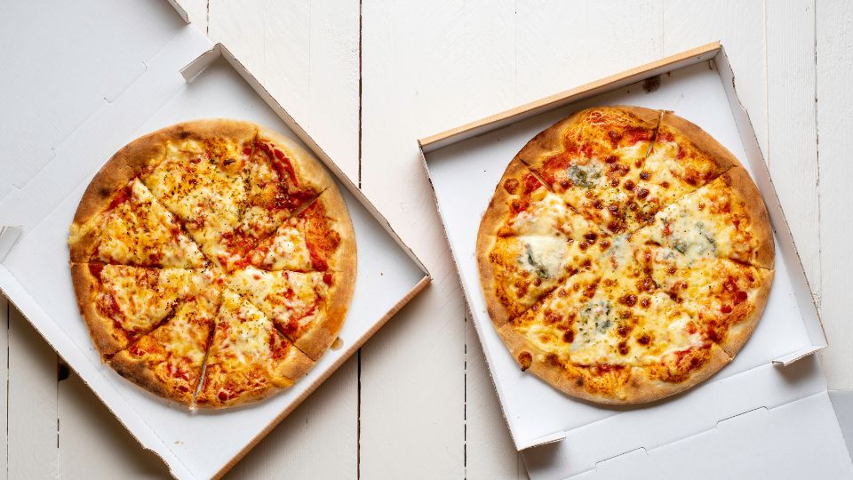 Two pizzas in carboard boxes.