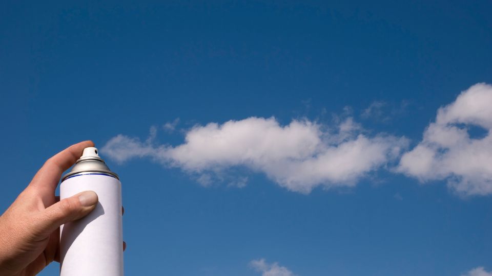 Aerosol can being sprayed into the sky, looking like clouds.