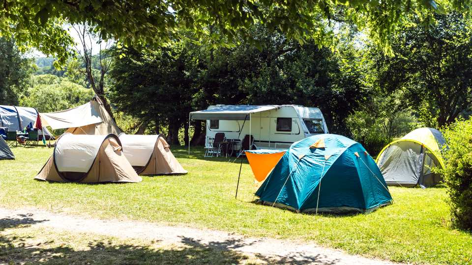 Campsite on a sunny day with tents and a caravan