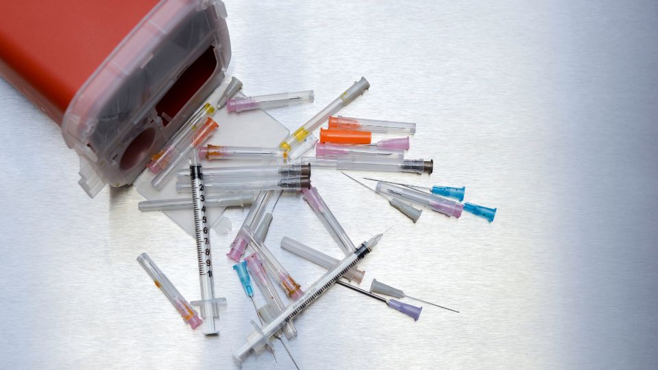 Sharps needles puring out of a sharps bin