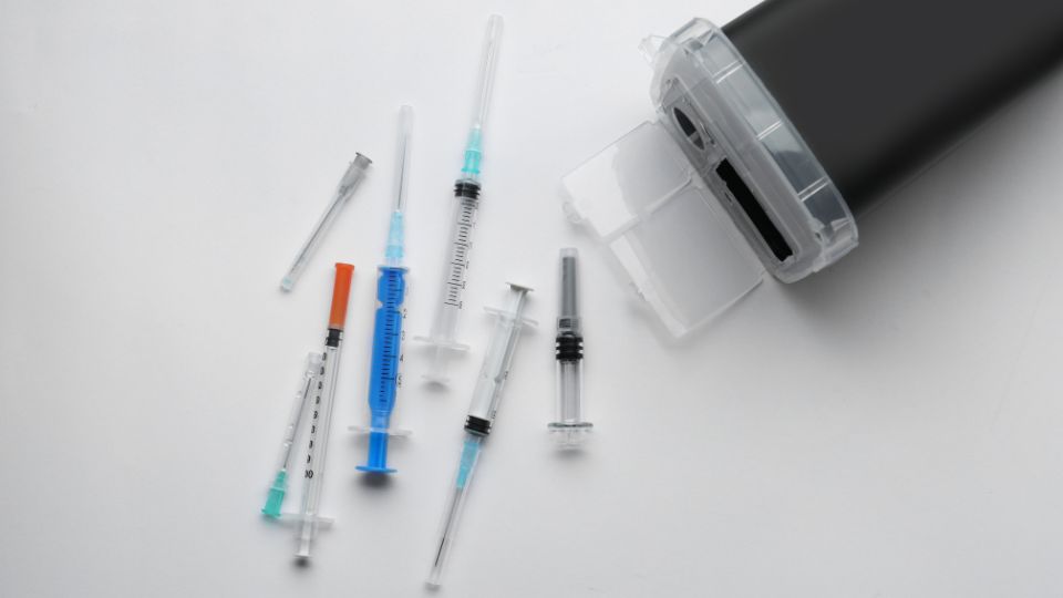Sharps waste needles coming out of a bin