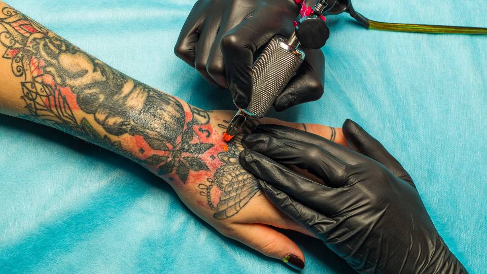 Tattoo artist colouring a tattoo on someones forearm