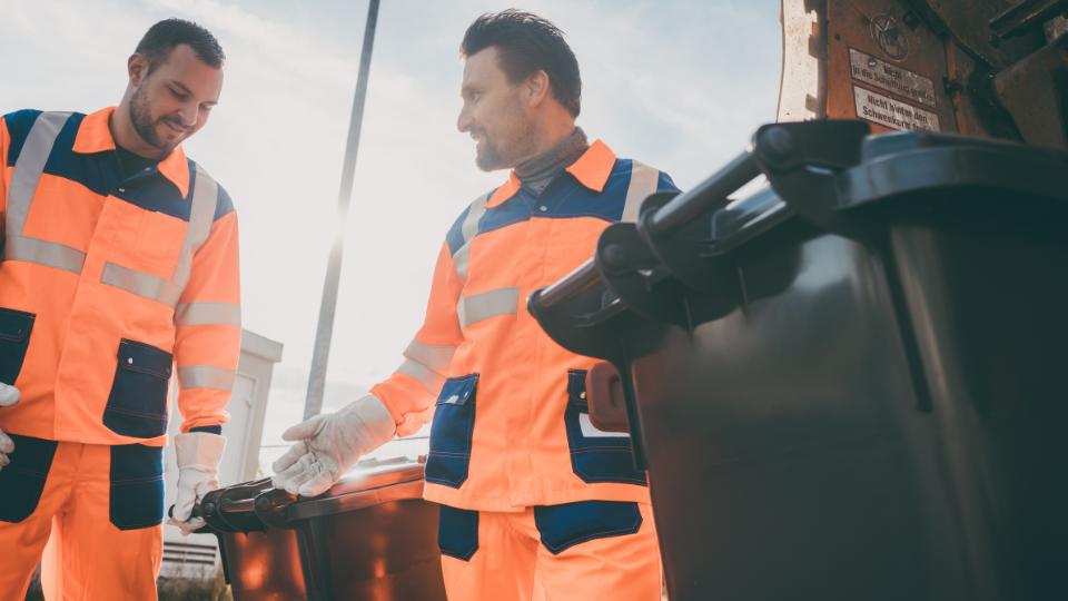 Two workers carrying out commercial recycling collection services in orange hi-vis jackets