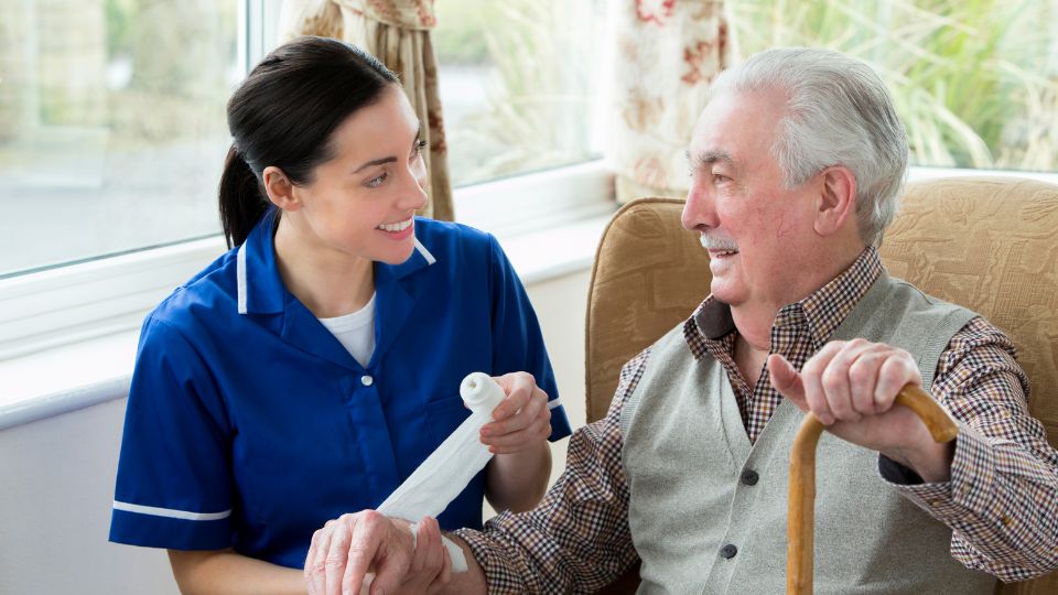 Care home staff bandaging an elderly resident